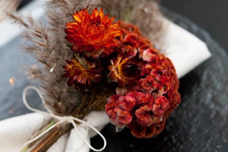 A closeup of bright red and fluffy dry flowers tied to a napkin.