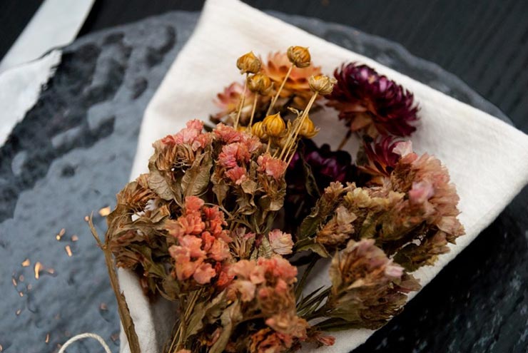 A closeup of bright, dry flowers tied to a napkin on a plate.