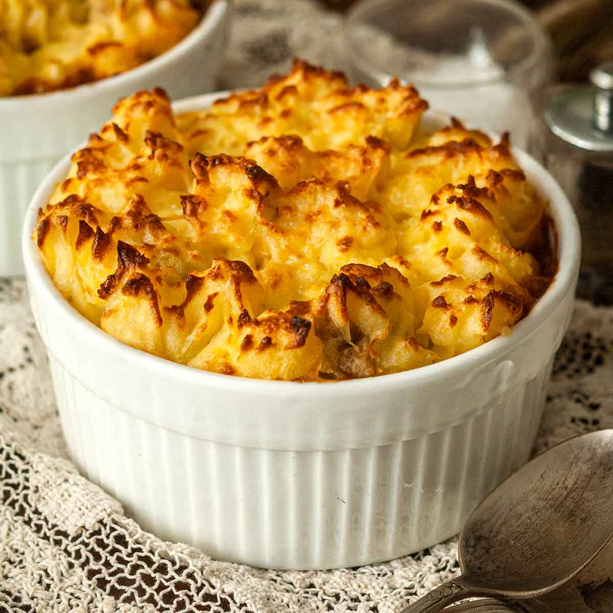 A shepherd's pie in a bowl on a lace table cloth.