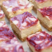 Raspberry marbled lemon cheesecake bars on a marble table.