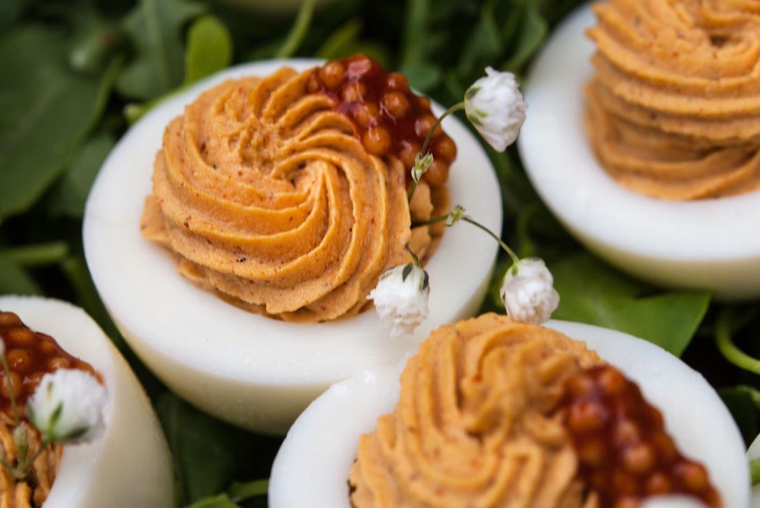 A few deviled eggs in arugula garnished with mustard caviar and baby's breath.