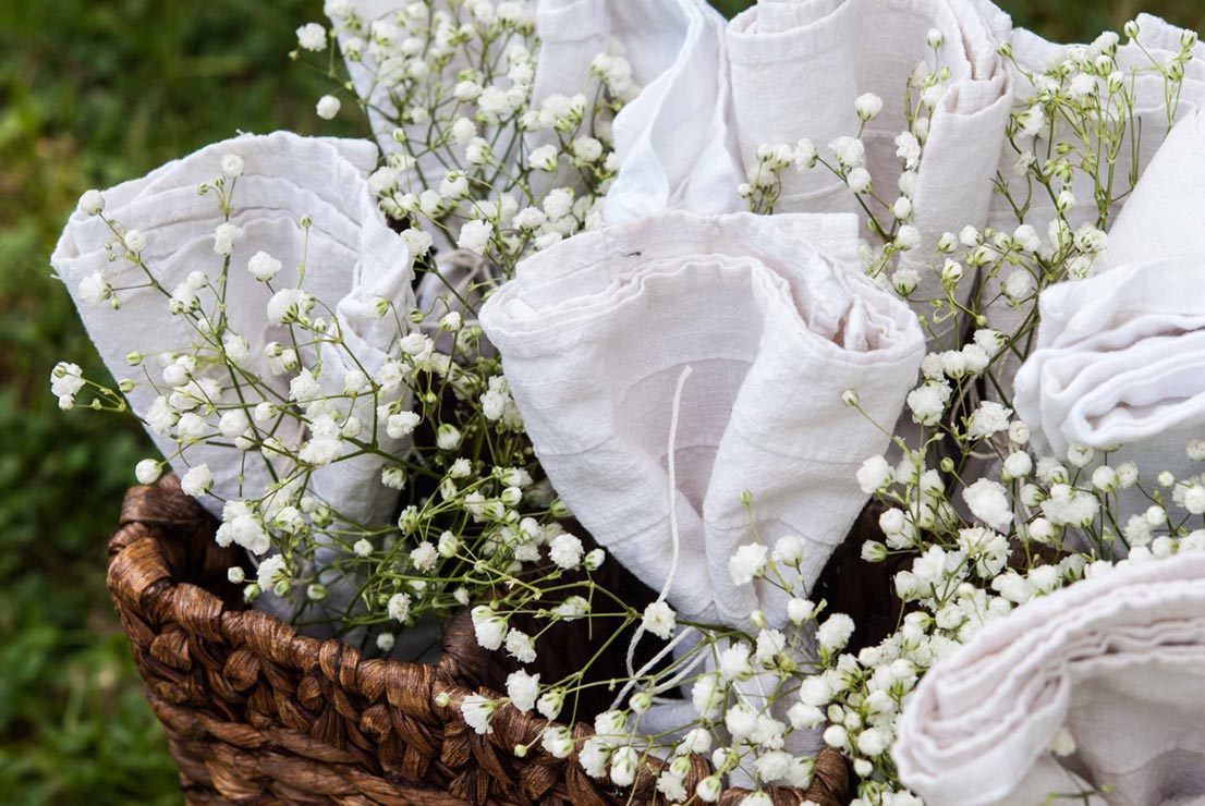 Napkins tied with string in a basket with baby's breath.