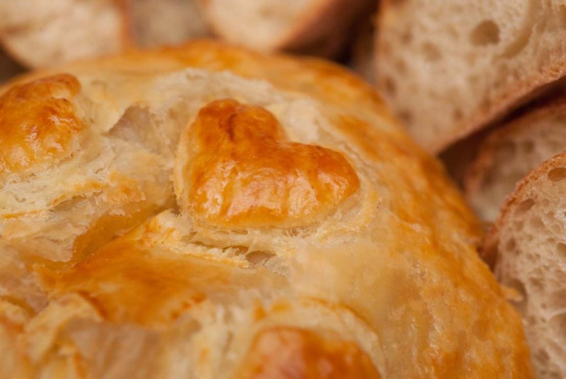 A closeup of a pastry heart on top of a baked gruyere.