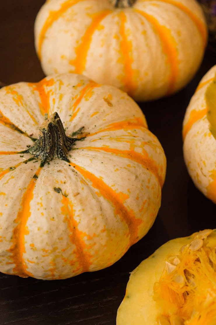 3 white pumpkin gourds with orange stripes on a black table