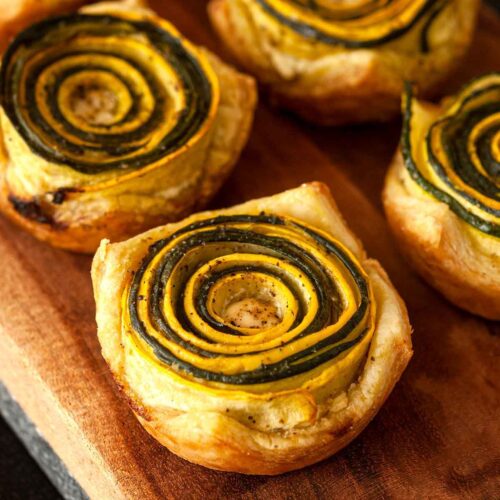 6 pesto zucchini rosettes on a wooden board.