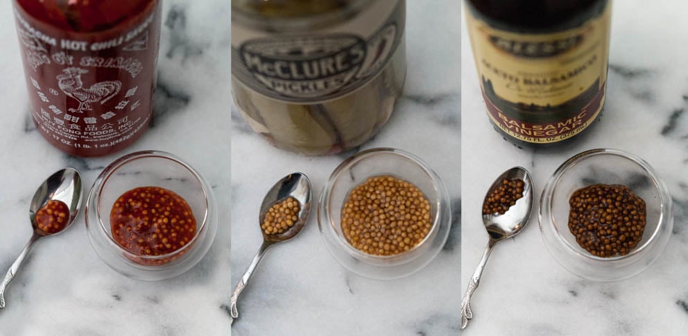 3 kinds of mustard caviar in small bowls on a marble table in front of 3 bottles.