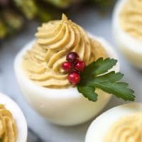 A deviled egg garnished with pepper corns and a leaf.