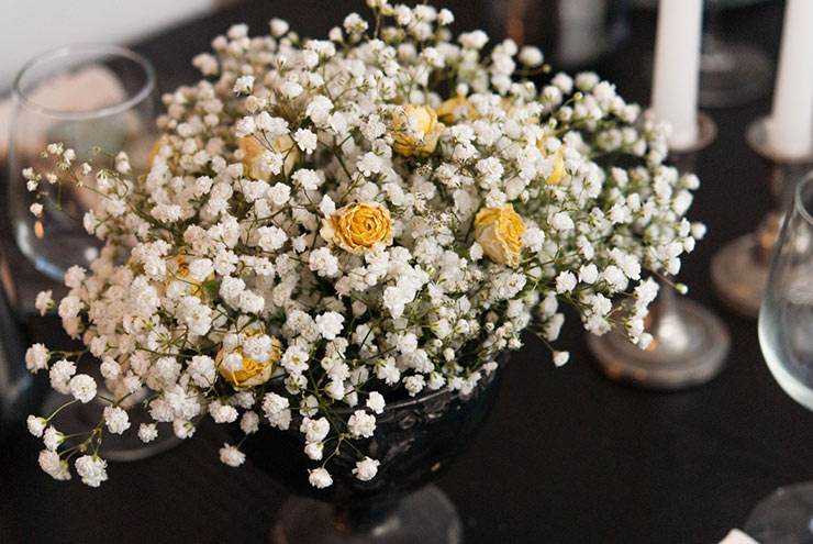 A bouquet with baby's breath and yellow roses on a table.