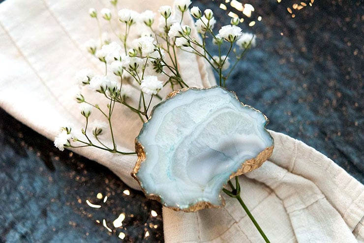 A blue and gold napkin ring holding napkin with baby's breath tucked into the napkin on a plate.