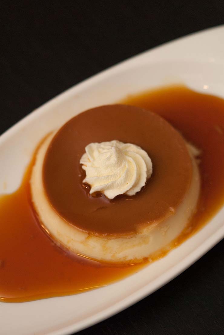 A Grand Marnier Custard on a white plate on a black table.