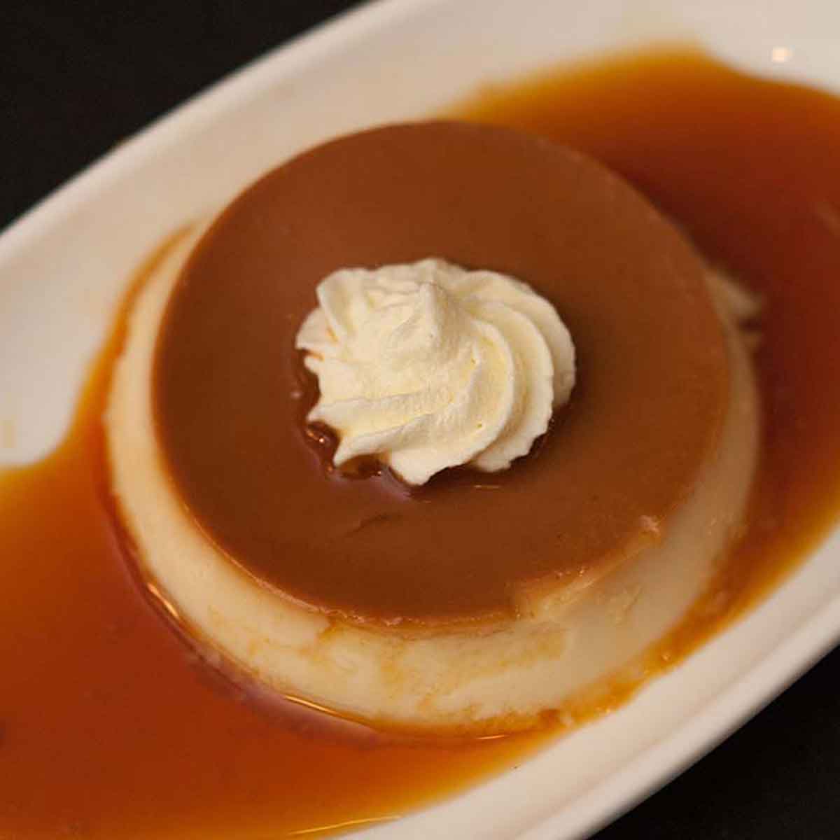 A Grand Marnier Custard on a white plate on a black table.