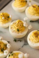 A marble slate with 5 deviled eggs, garnished with thyme and baby's breath.