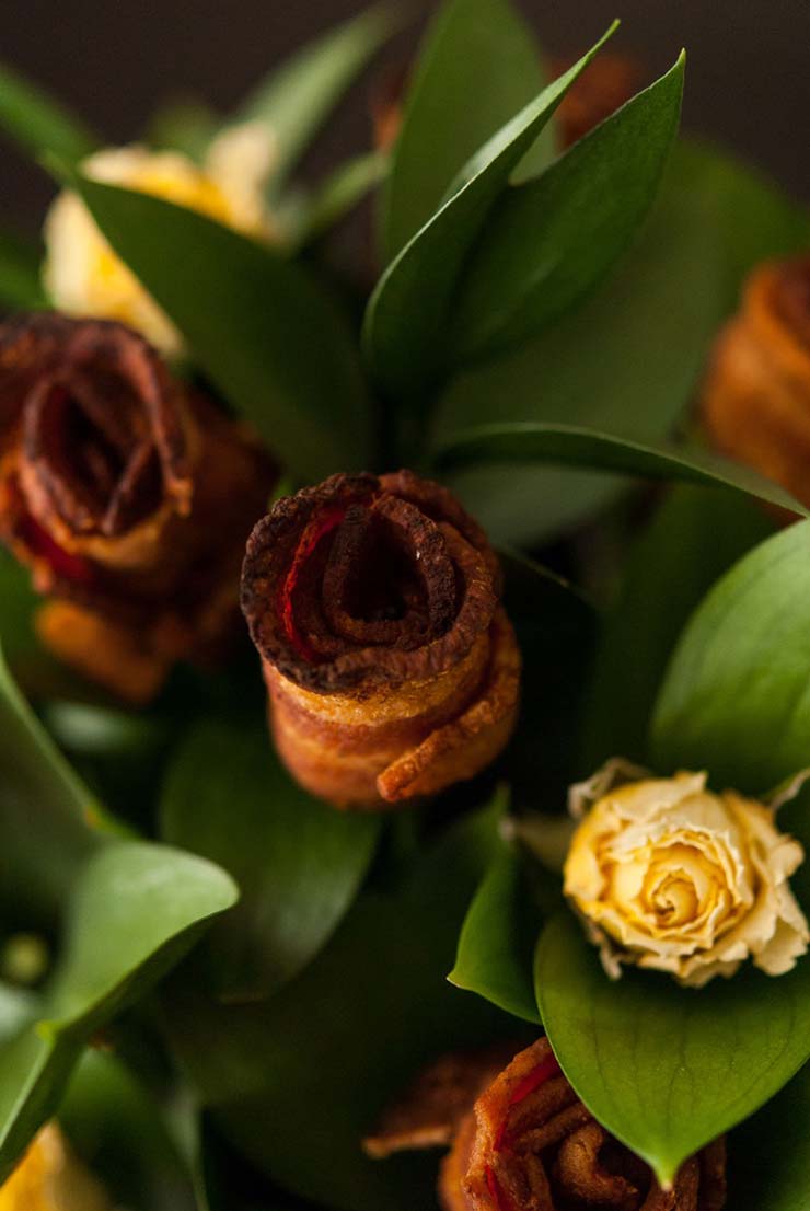 A bacon rose next to yellow roses in a bouquet.