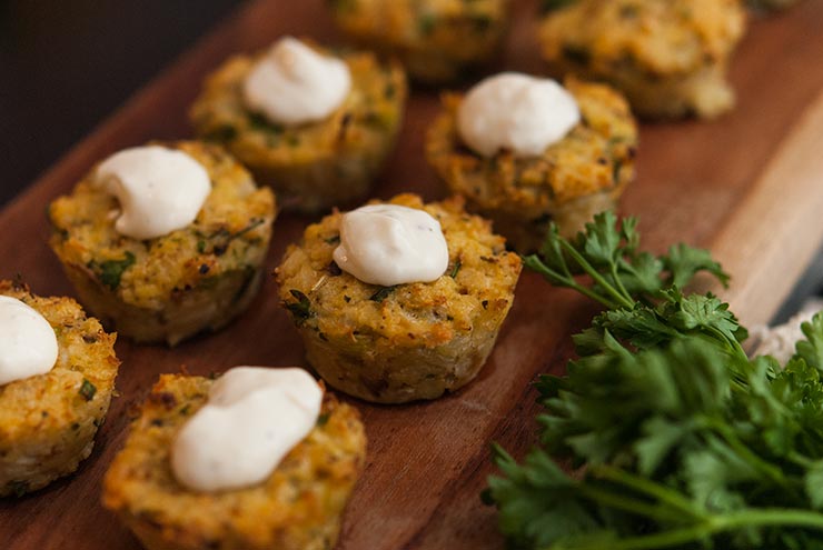 Cauliflower cakes on a wooden board, topped with cream.