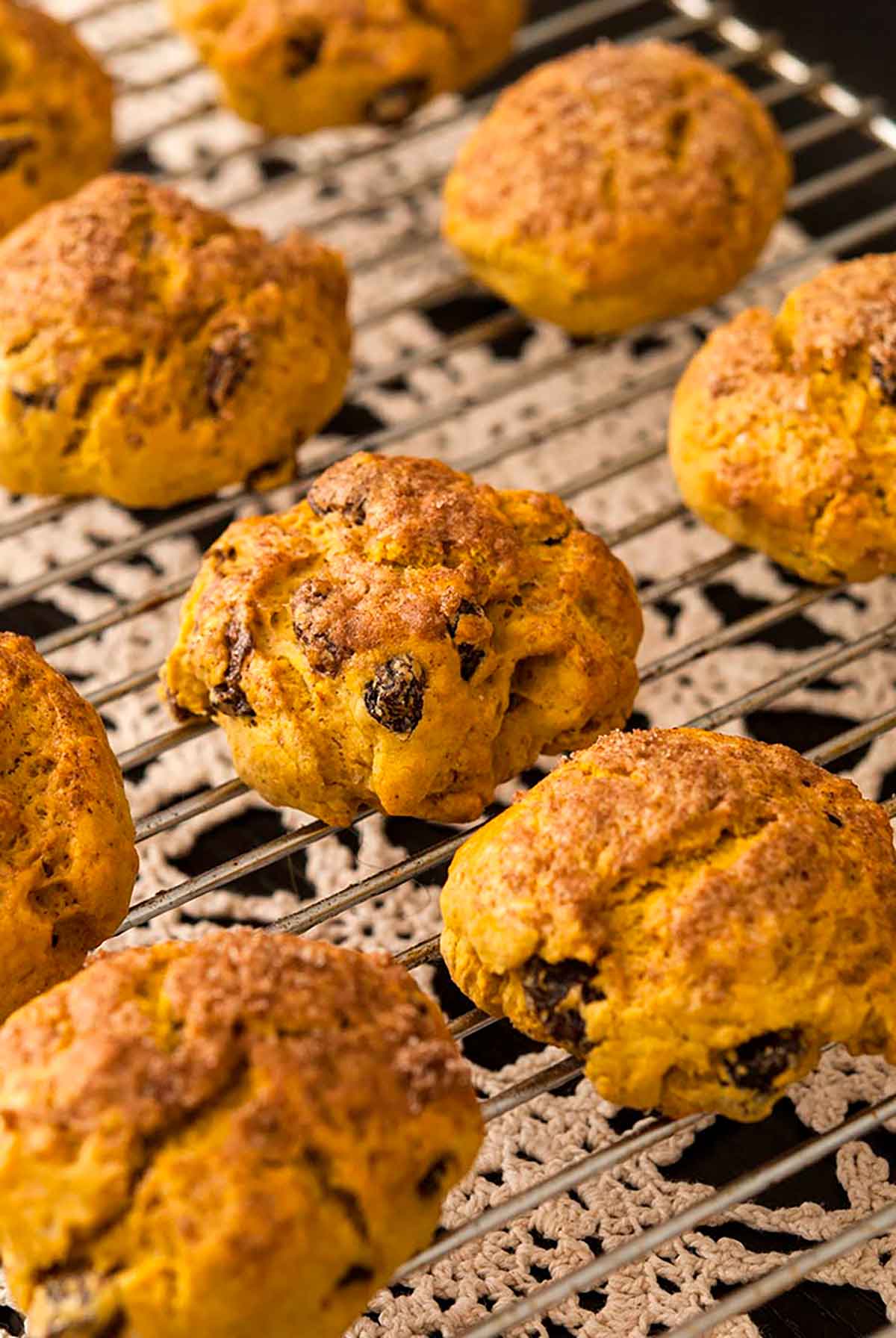 Pumpkin scones cooling on a wrack over a lace tablecloth.