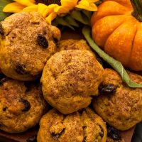 Pumpkin scones beside a small pumpkin and sunflower on a wooden board.