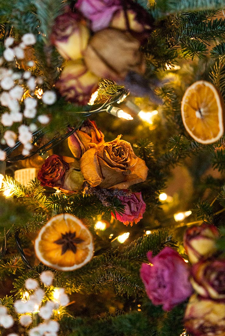 a colorful christmas tree decorated with flowers and dried orange slices.