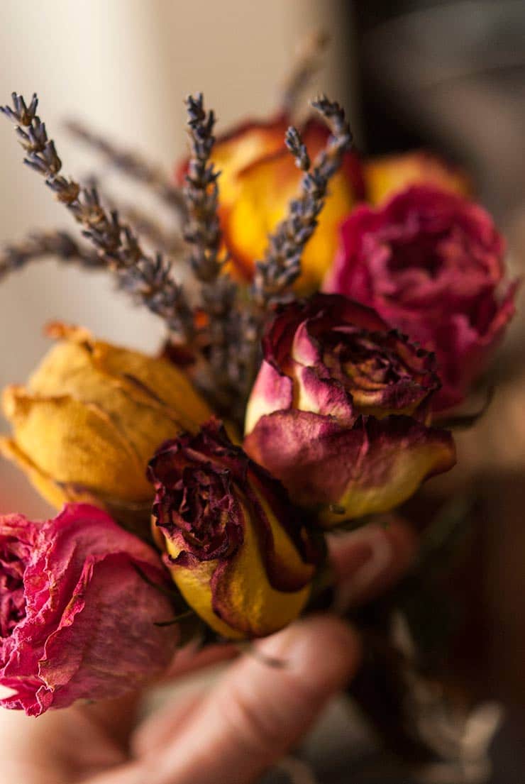 A hand holding a small bouquet of roses and lavender.