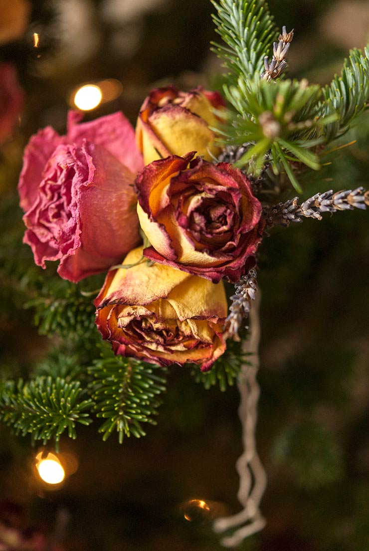 A small bouquet of roses and lavender tied to a Christmas tree bough.