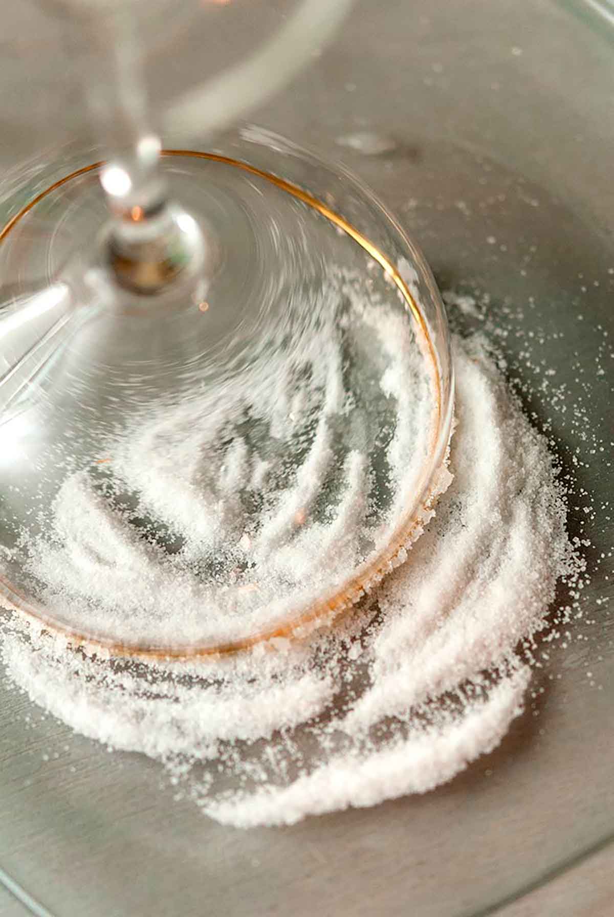 A cocktail glass pressed into sugar on a plate.