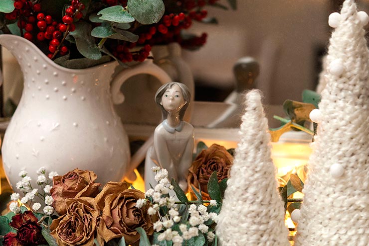 Floral Christmas decorations and trees made of yarn on a mantle.