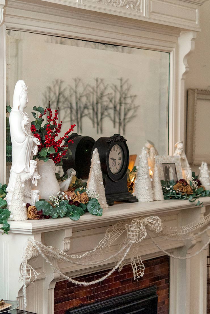 Floral Christmas decorations and trees made of yarn on a mantle.