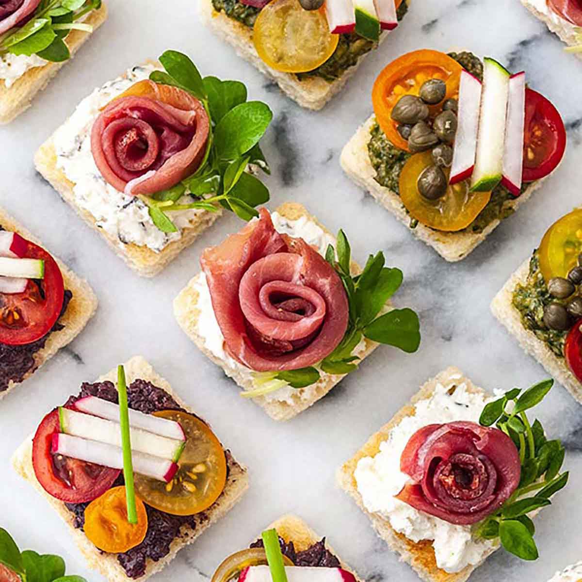 A marble appetizer tray of 8 canapés in 3 different styles.