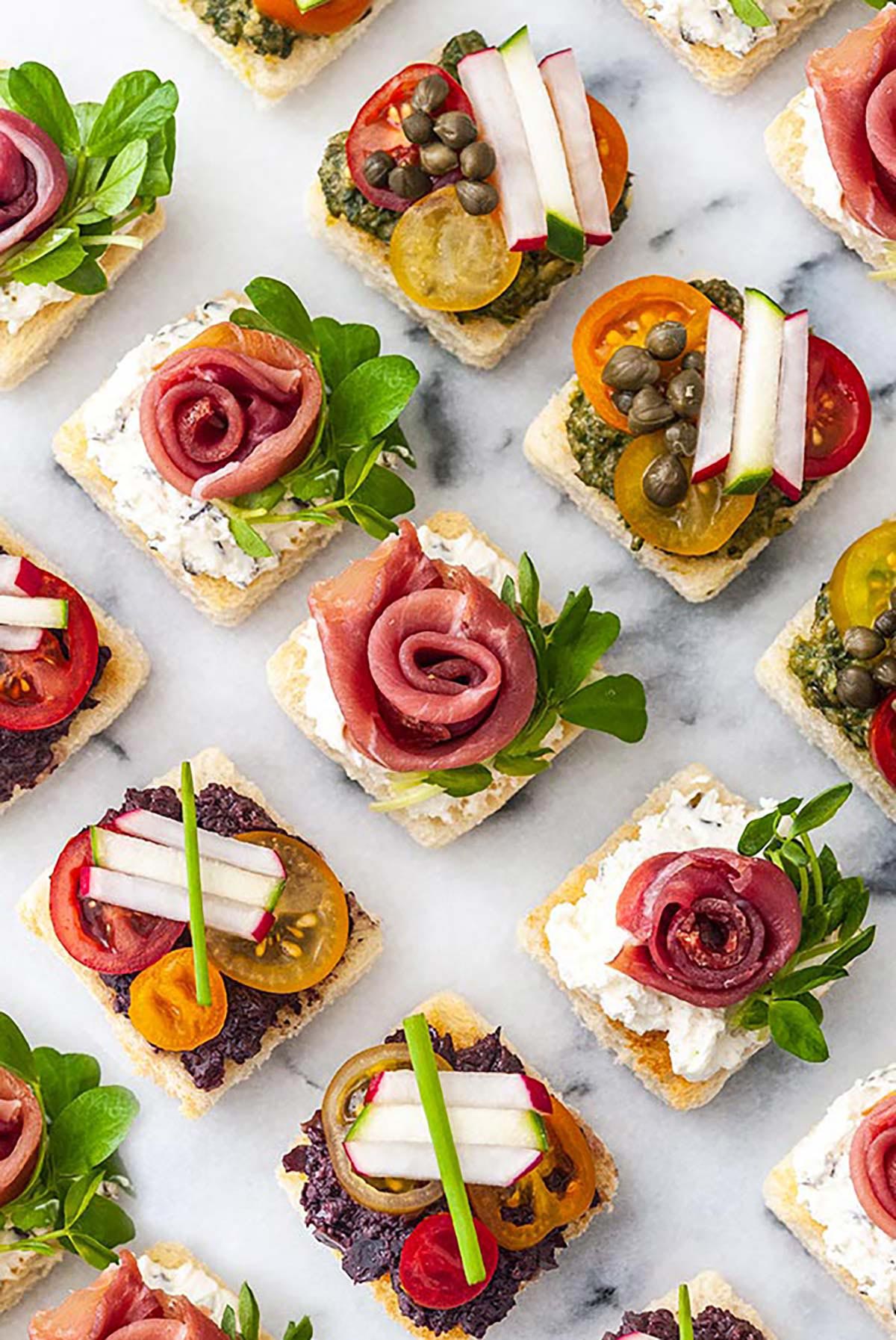 A marble appetizer tray of 15 canapés in 3 different styles.