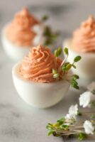 3 pink deviled eggs beside flowers.