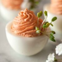 A pink deviled eggs beside flowers.