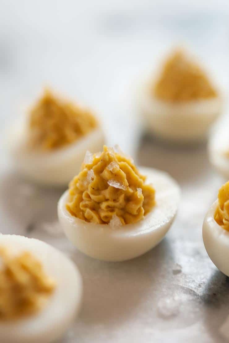 A small deviled quail egg on a marble table, surrounded by 4 others.