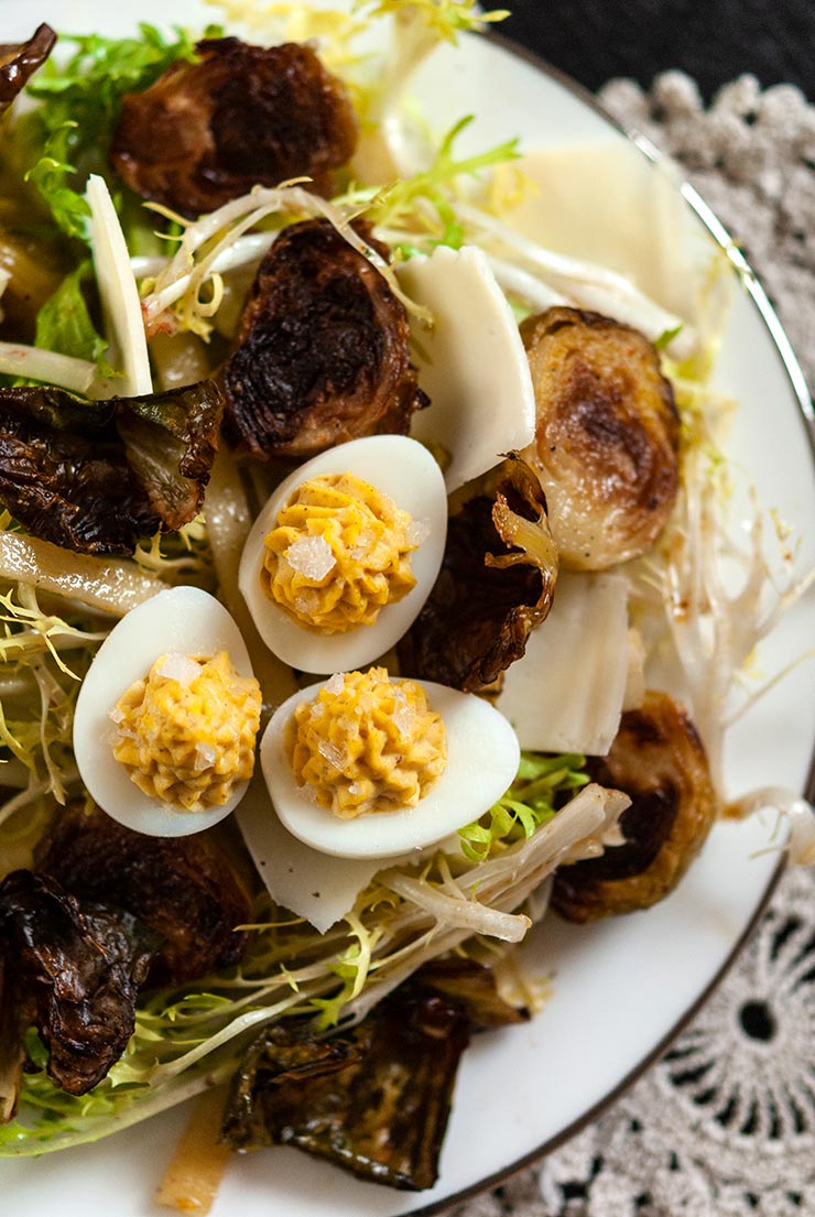 A plate of Brussels sprouts salad topped with quail deviled eggs.