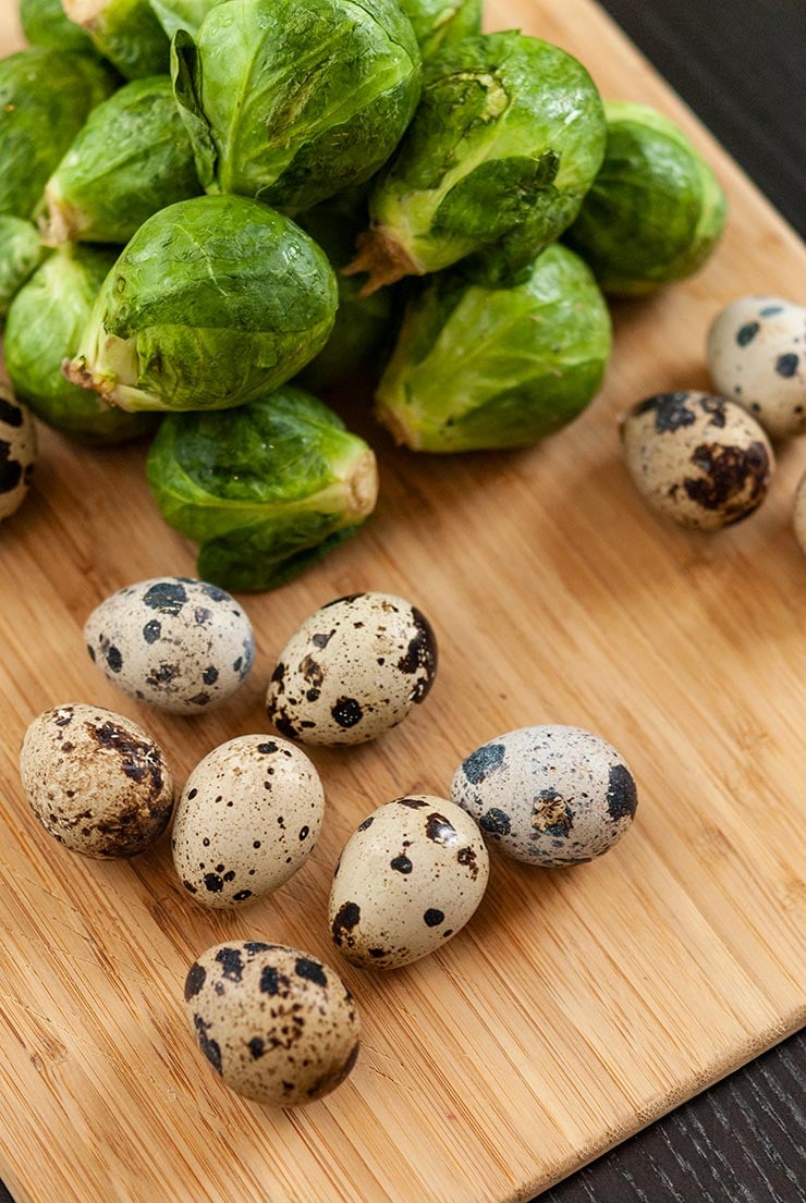 Quail eggs and Brussels sprouts on a cutting board.