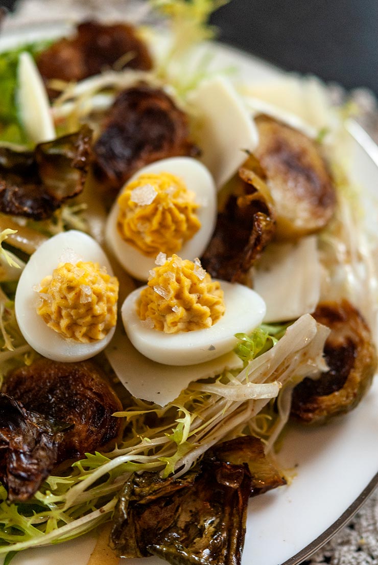 A plate of Brussels sprouts salad topped with quail deviled eggs.