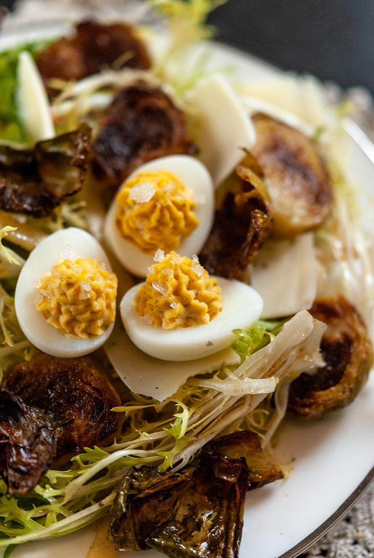 A plate of Brussels sprouts salad topped with quail deviled eggs.