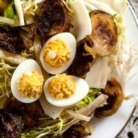 A plate of Brussels sprouts salad topped with quail deviled eggs.