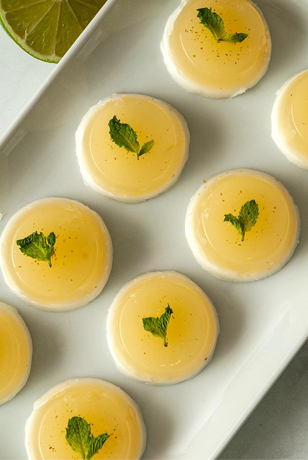8 coconut mojito jello shots on a plate, garnished with mint from above.