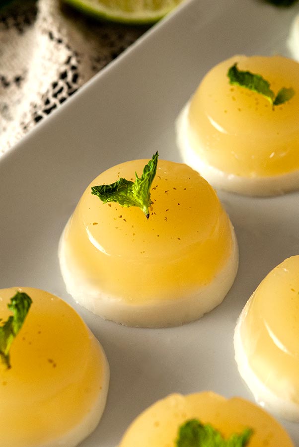 A coconut mojito jello shot on a plate surrounded by 3 others.