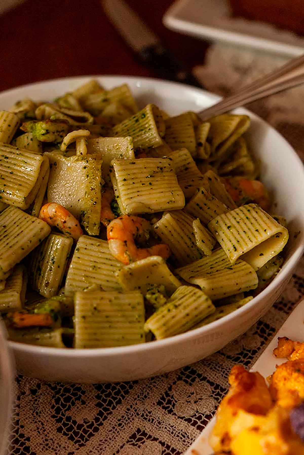 A large bowl of pesto pasta with small shrimp.