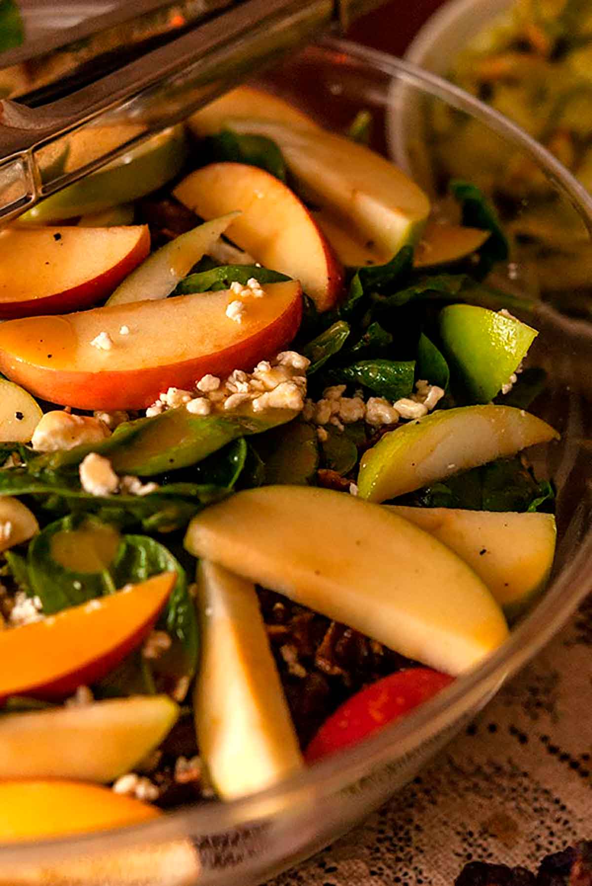 A large bowl of salad with apples, sprinkled with cheese.