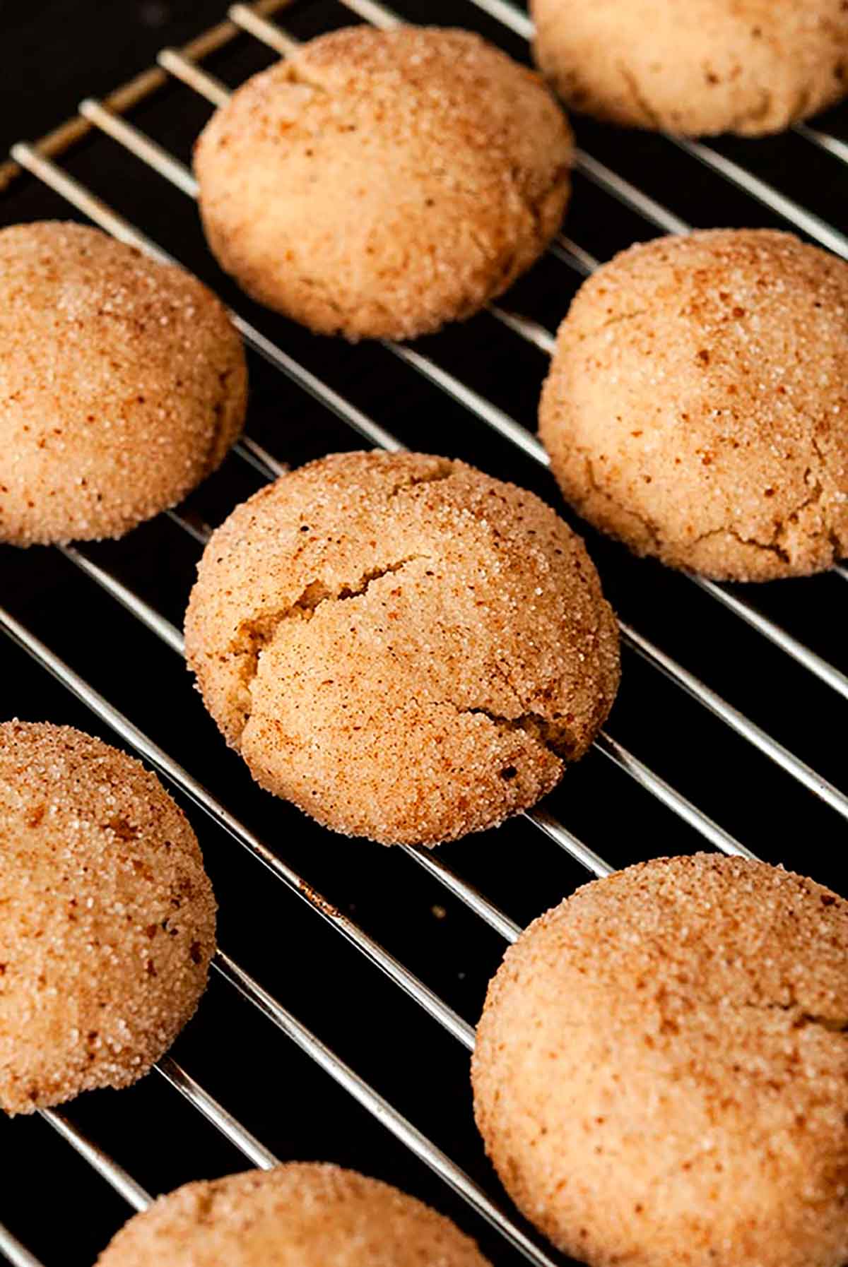 8 baked snickerdoodles on a baking rack.