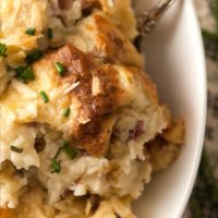 A bowl of baked mashed potatoes on a table with a lace tablecloth.