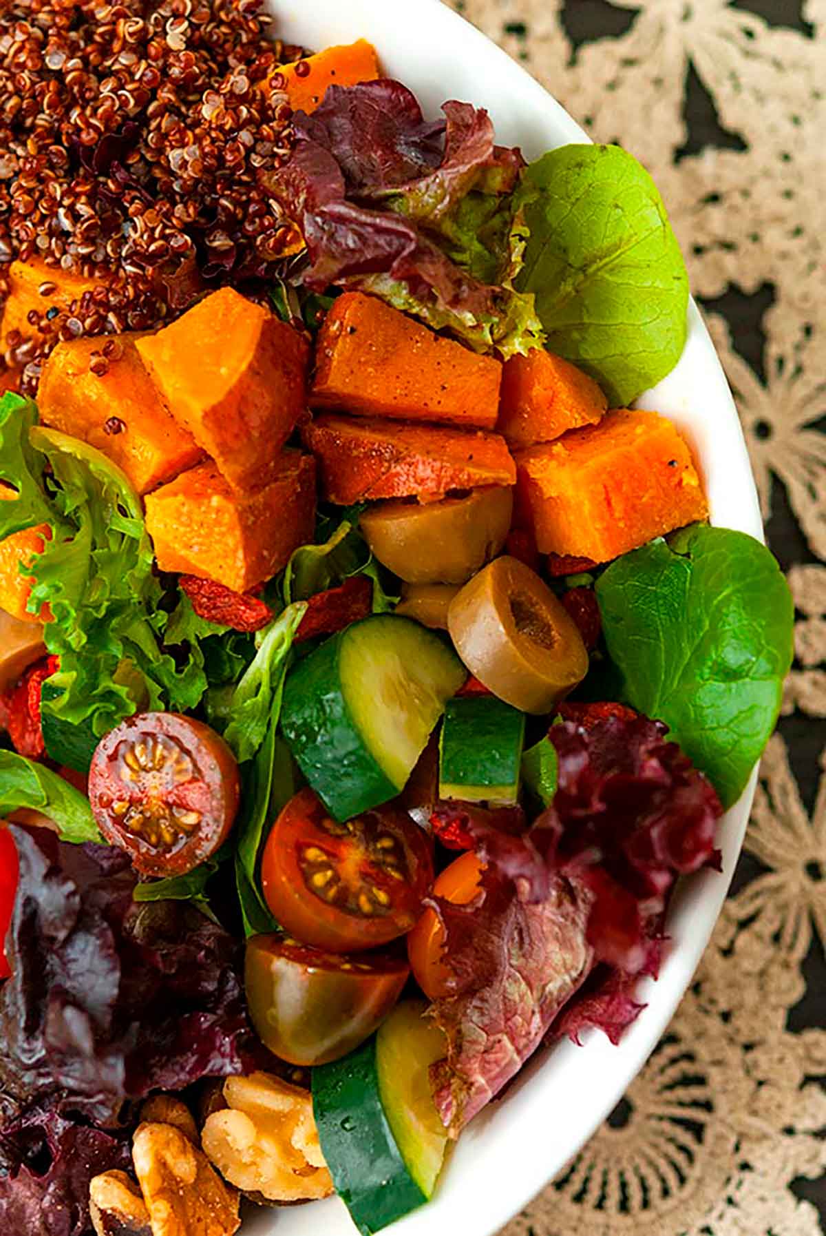 A colorful salad on a table with a lace tablecloth.