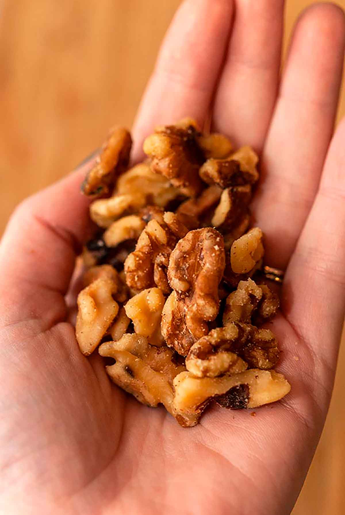 A hand holding walnuts.