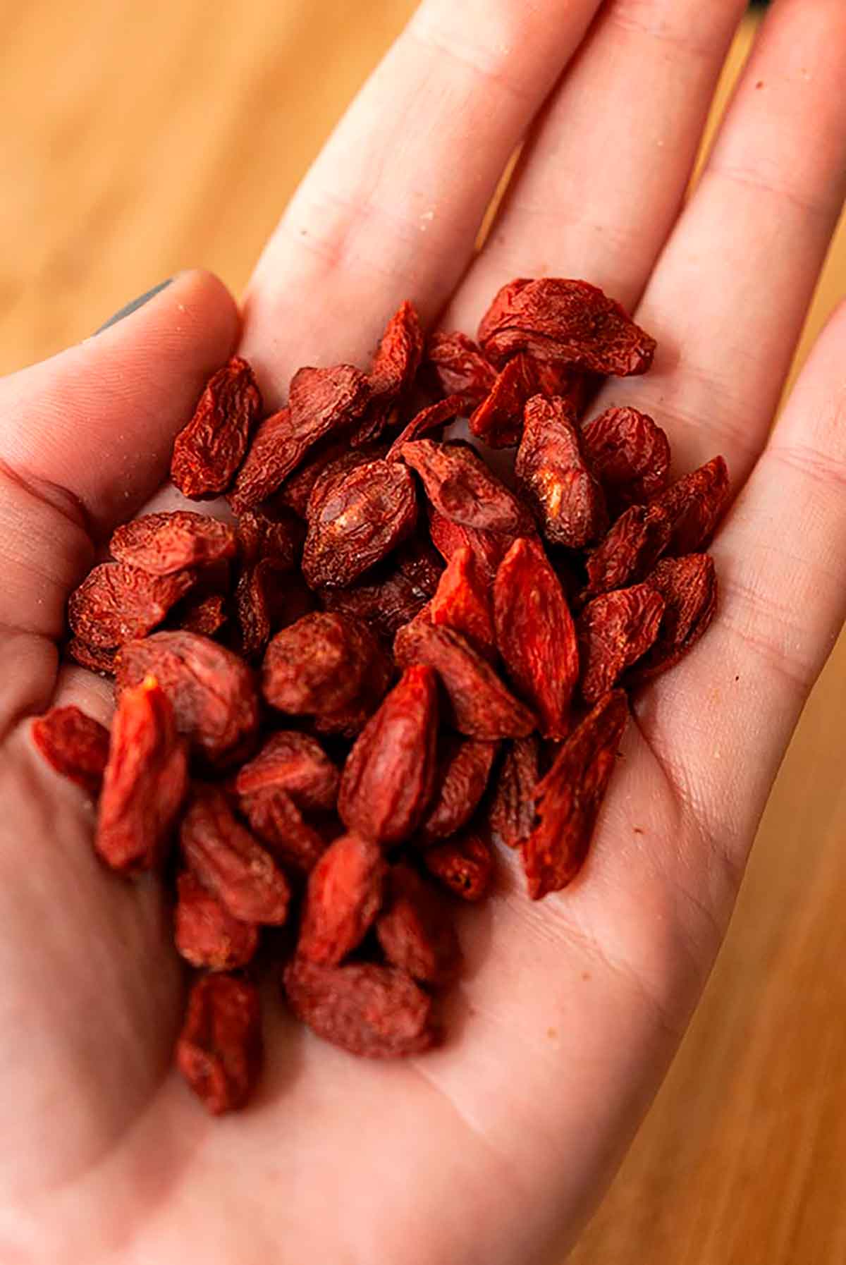 A hand holding goji berries.