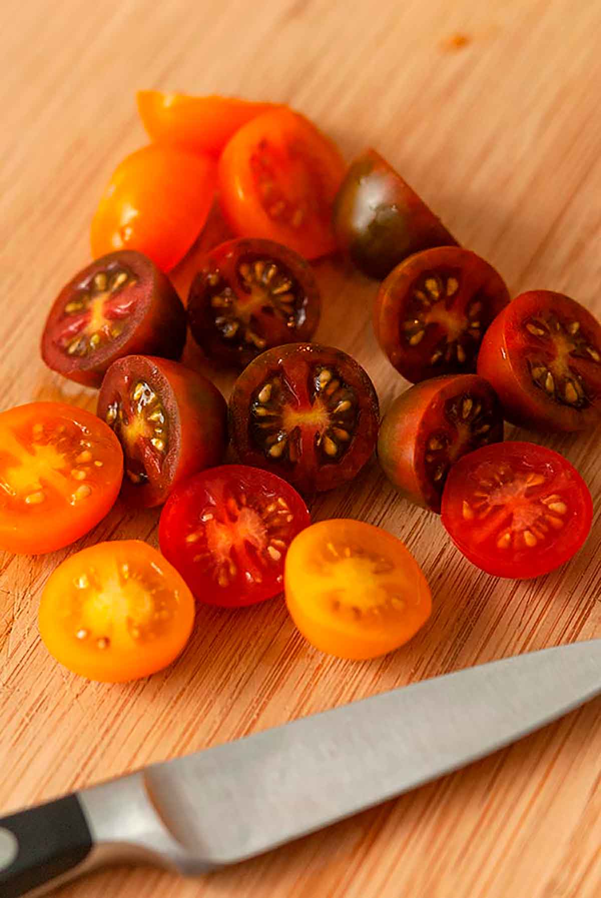 About 15 chopped cherry tomatoes on a cutting board.