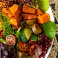 A colorful salad on a table with a lace tablecloth.