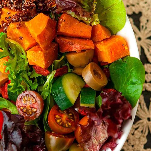 A colorful salad on a table with a lace tablecloth.