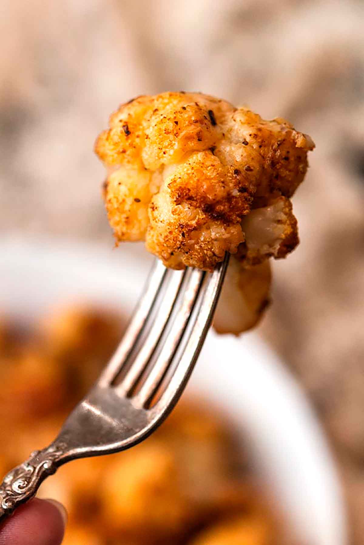 A small roasted cauliflower florette on an antique fork.