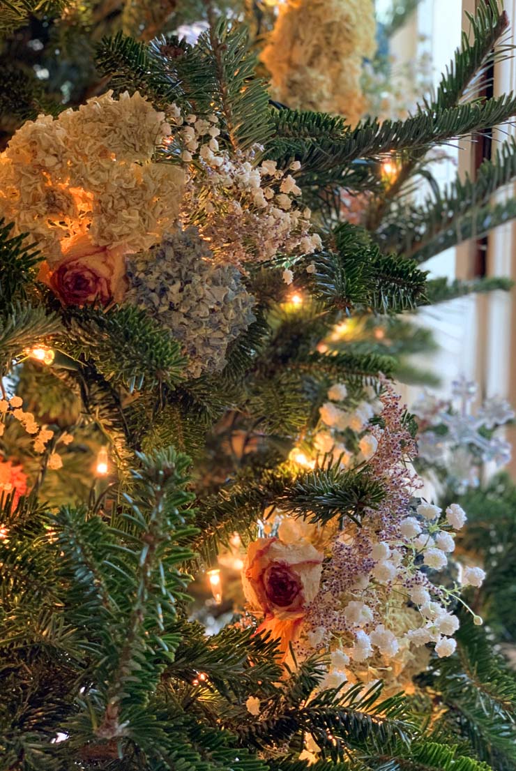 A Christmas tree with textural flower decorations and lights.